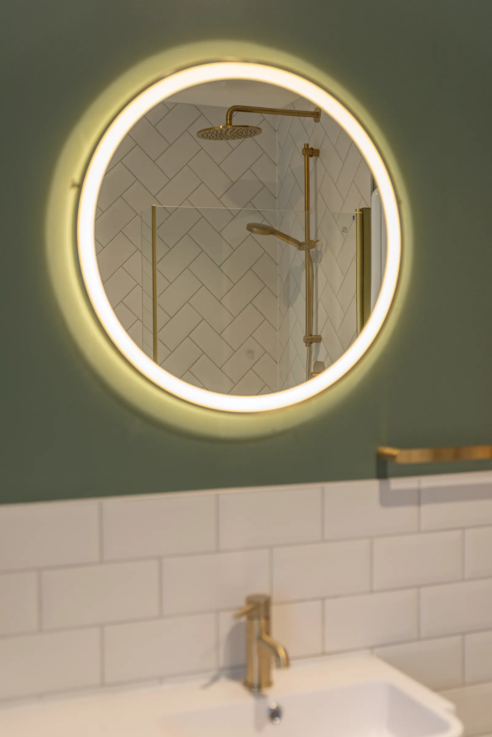 A bathroom with a sink and a round mirror.