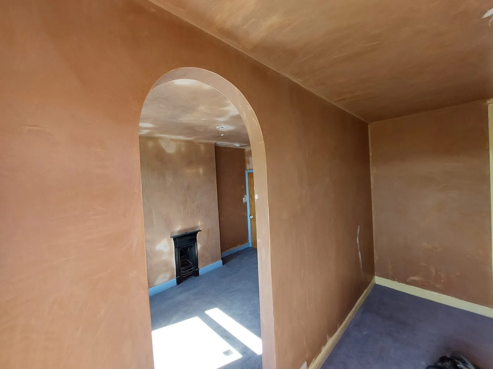 An empty room with a fireplace in the corner.