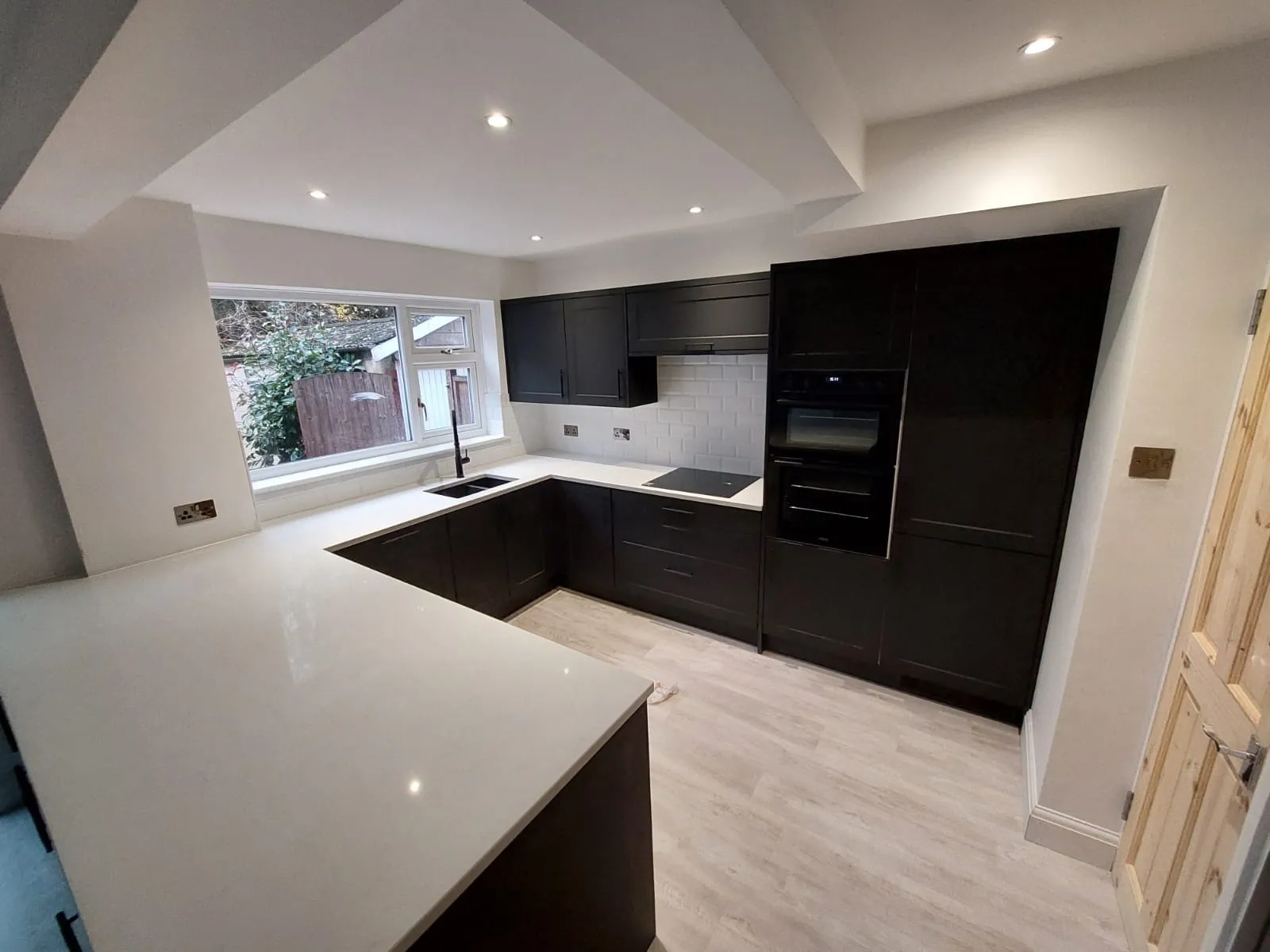 A kitchen with a white counter top next to a window.